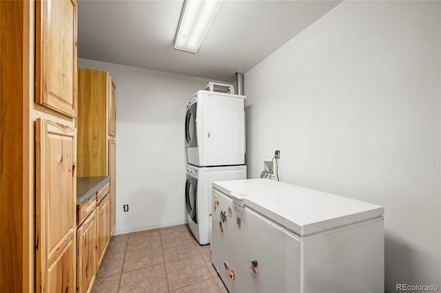 laundry room featuring stacked washer / drying machine, cabinet space, and light tile patterned floors