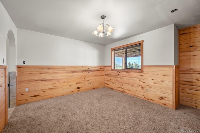 empty room featuring a wainscoted wall, wooden walls, and carpet flooring