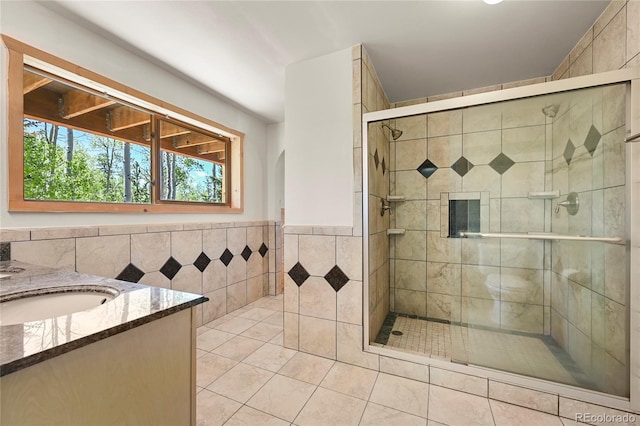 full bath with a stall shower, tile patterned flooring, tile walls, and vanity