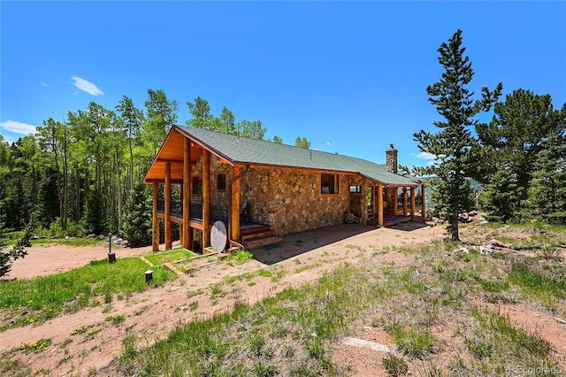 exterior space with stone siding and a chimney