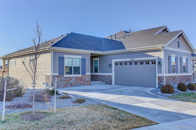 view of front of property featuring stone siding, roof with shingles, an attached garage, and driveway