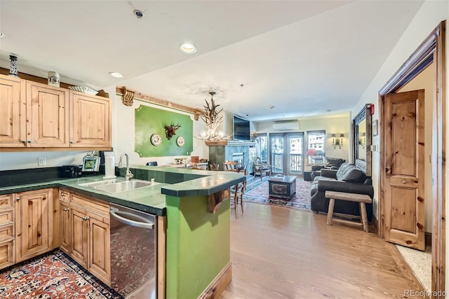 kitchen featuring sink, a wall mounted air conditioner, light hardwood / wood-style floors, stainless steel dishwasher, and kitchen peninsula