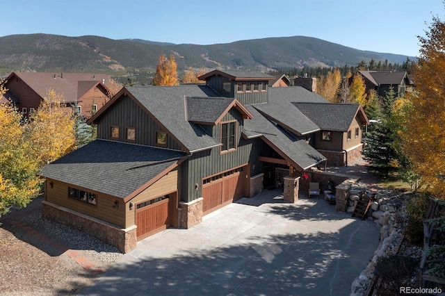 27 Habitat, Dillon, CO 80435 - view of front of home with board and batten siding, stone siding, a shingled roof, driveway, and a mountain view