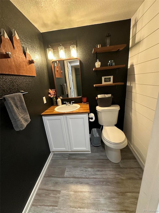 11975 Riverstone Cir Unit 9C, Commerce City, CO 80640 - bathroom featuring wood finished floors, a textured wall, a textured ceiling, and vanity
