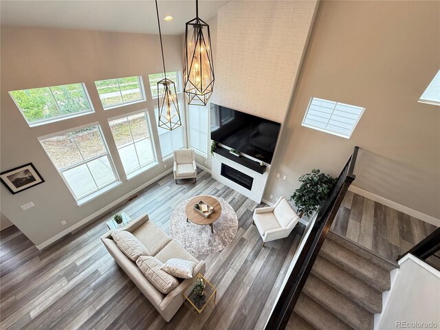 1732 Stable View Dr, Castle Pines, CO 80108 - living room featuring a high ceiling, wood finished floors, baseboards, stairway, and a fireplace