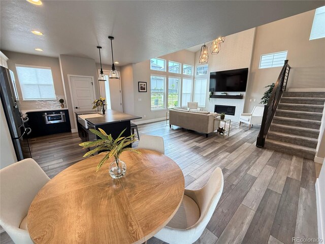 1732 Stable View Dr, Castle Pines, CO 80108 - dining area featuring a fireplace, wood finished floors, stairs, baseboards, and recessed lighting