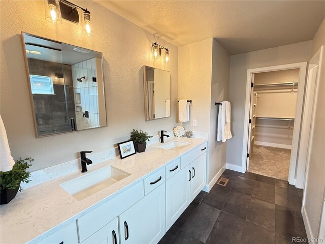 1732 Stable View Dr, Castle Pines, CO 80108 - bathroom featuring a stall shower, double vanity, a spacious closet, a textured wall, and a textured ceiling