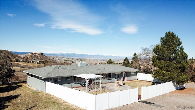 back of property with roof with shingles, a fenced backyard, a sunroom, a mountain view, and a patio