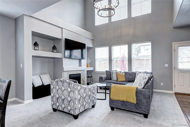 carpeted living room featuring a healthy amount of sunlight, a notable chandelier, built in features, and a fireplace