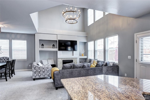 dining area featuring a tile fireplace, a chandelier, and light colored carpet