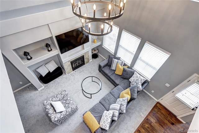 living room featuring a tiled fireplace, a chandelier, and wood-type flooring