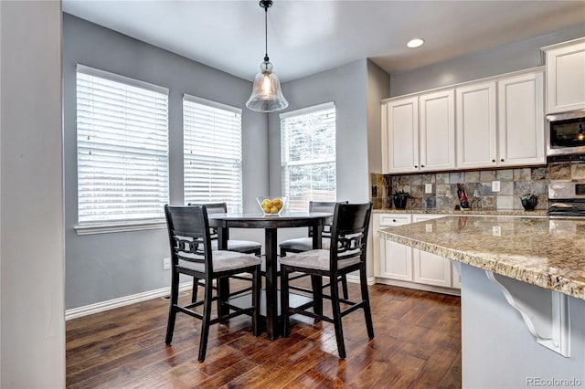 kitchen with stainless steel appliances, white cabinetry, light stone counters, tasteful backsplash, and hanging light fixtures