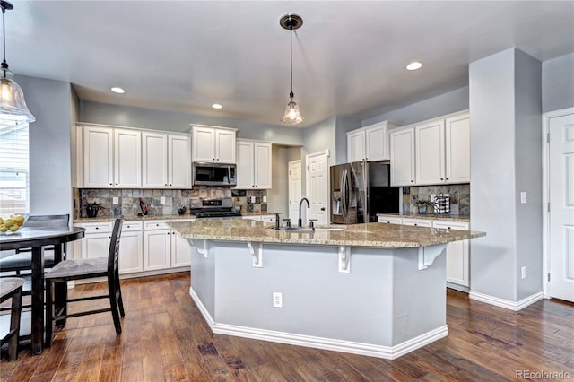 kitchen featuring stainless steel appliances, white cabinetry, and hanging light fixtures