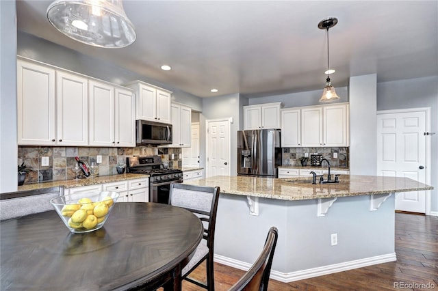 kitchen with white cabinets, stainless steel appliances, an island with sink, and sink