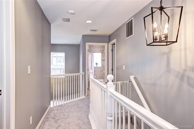 hallway featuring carpet flooring and a chandelier