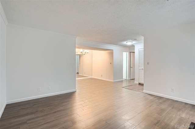 5300 E Cherry Creek S Drive 217, Denver, CO 80246 - unfurnished room featuring crown molding, a textured ceiling, a chandelier, wood finished floors, and baseboards