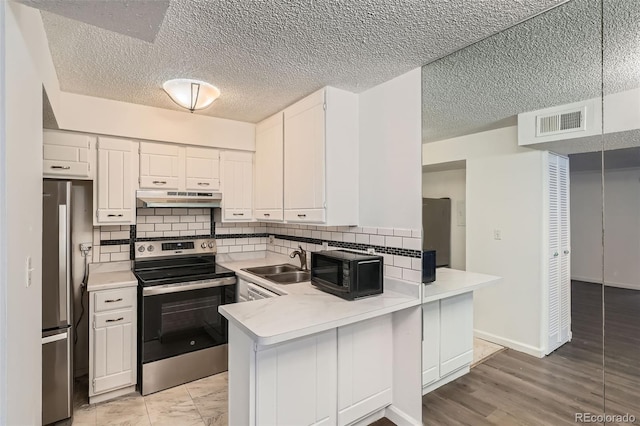 5300 E Cherry Creek S Drive 217, Denver, CO 80246 - kitchen featuring appliances with stainless steel finishes, under cabinet range hood, a sink, a peninsula, and light countertops