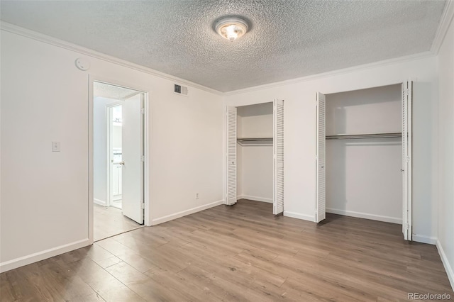 5300 E Cherry Creek S Drive 217, Denver, CO 80246 - unfurnished bedroom with two closets, crown molding, a textured ceiling, wood finished floors, and baseboards