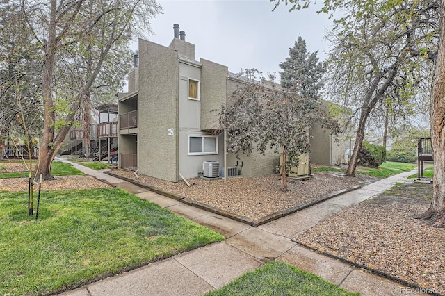 5300 E Cherry Creek S Drive 217, Denver, CO 80246 - view of home's exterior with a yard, a chimney, stucco siding, and central AC