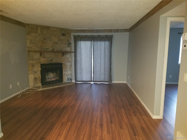 unfurnished living room featuring a textured ceiling, a fireplace, baseboards, and wood finished floors