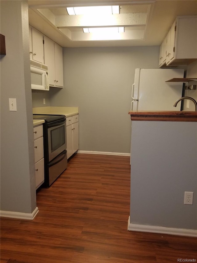 kitchen featuring dark wood-type flooring, white appliances, white cabinetry, and baseboards