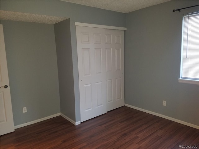 unfurnished bedroom with multiple windows, dark wood finished floors, and a textured ceiling