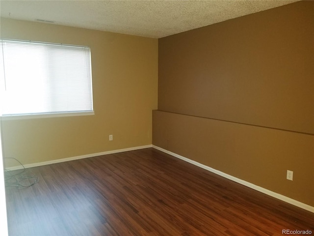 spare room with baseboards, dark wood-style flooring, and a textured ceiling