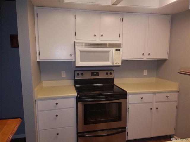 kitchen with white cabinets, white microwave, stainless steel electric range oven, and light countertops