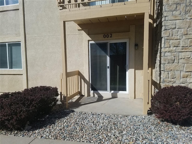 entrance to property featuring stone siding and stucco siding