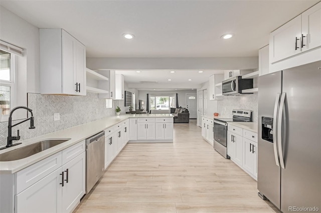 7752 Meade St, Westminster, CO 80030 - kitchen with stainless steel appliances, open shelves, a sink, a peninsula, and light wood-type flooring