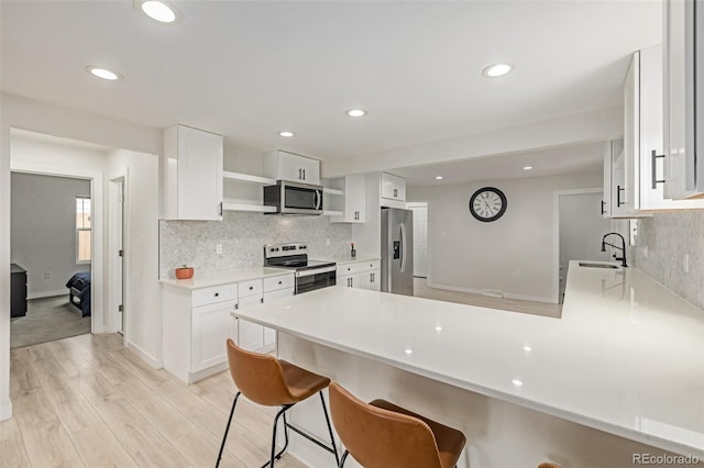 7752 Meade St, Westminster, CO 80030 - kitchen with stainless steel appliances, open shelves, a sink, a peninsula, and white cabinetry