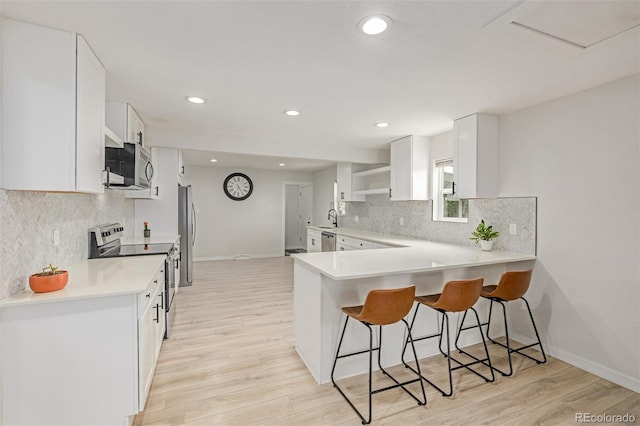 7752 Meade St, Westminster, CO 80030 - kitchen with stainless steel appliances, a sink, a breakfast bar area, open shelves, and white cabinets