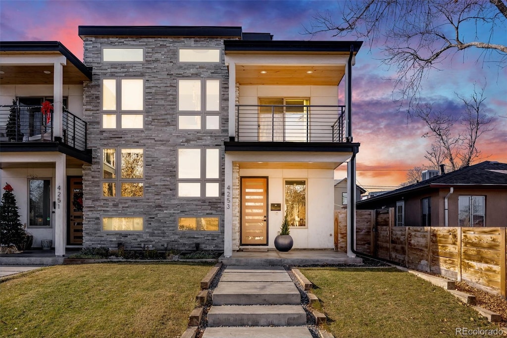 contemporary home with a balcony and a yard