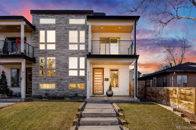 contemporary home with a balcony and a yard