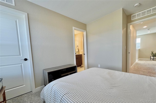 bedroom featuring light colored carpet and connected bathroom