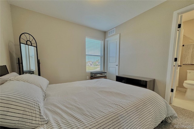 bedroom with ensuite bathroom and carpet flooring