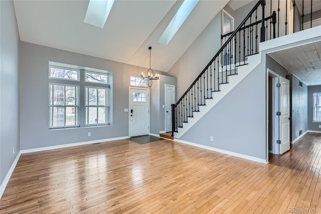 entryway with baseboards, a notable chandelier, stairway, wood-type flooring, and a skylight