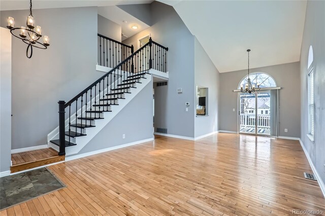 unfurnished living room with visible vents, hardwood / wood-style floors, an inviting chandelier, and stairs