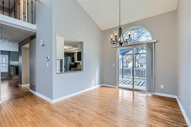 interior space featuring baseboards, hardwood / wood-style floors, a notable chandelier, and plenty of natural light