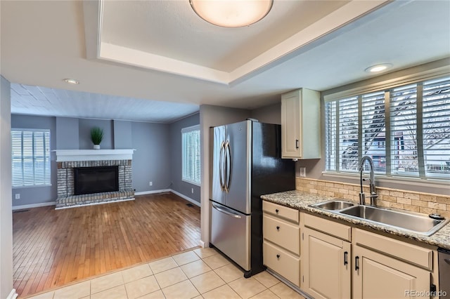kitchen featuring plenty of natural light, a tray ceiling, freestanding refrigerator, and a sink