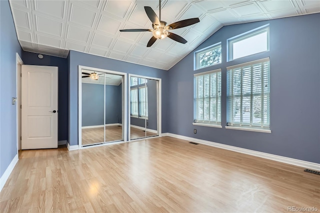 unfurnished bedroom featuring baseboards, visible vents, multiple windows, and two closets