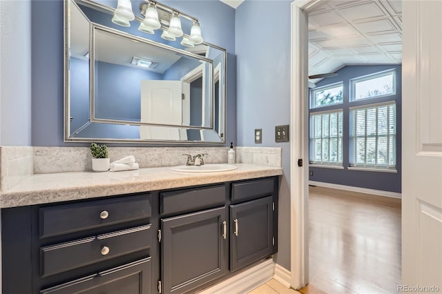 bathroom with baseboards, vanity, and vaulted ceiling