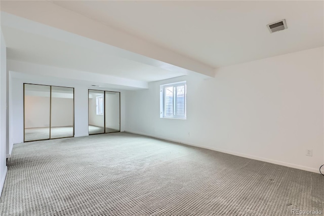 spare room with visible vents, baseboards, light colored carpet, and beamed ceiling
