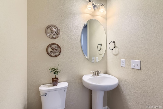 half bathroom featuring toilet and a textured wall