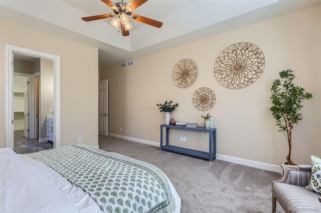 bedroom with a tray ceiling, carpet flooring, visible vents, and baseboards