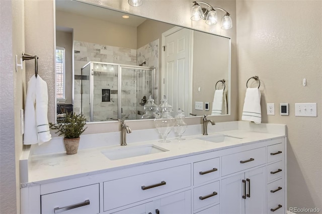 bathroom with double vanity, a stall shower, and a sink