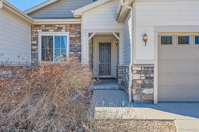 view of exterior entry with an attached garage and stone siding