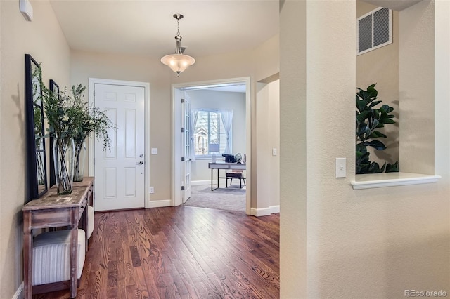 foyer entrance with dark wood finished floors, visible vents, and baseboards