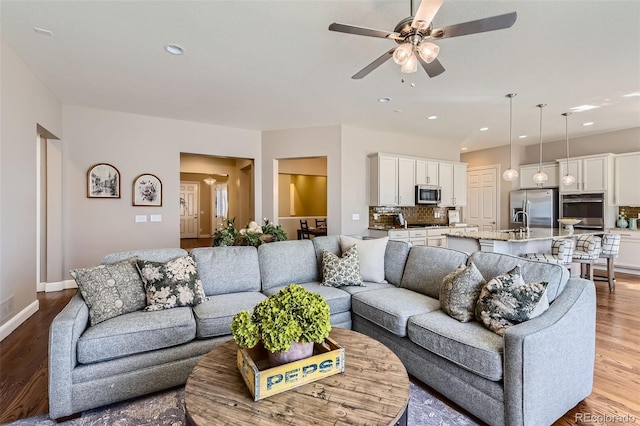 living room featuring baseboards, ceiling fan, wood finished floors, and recessed lighting