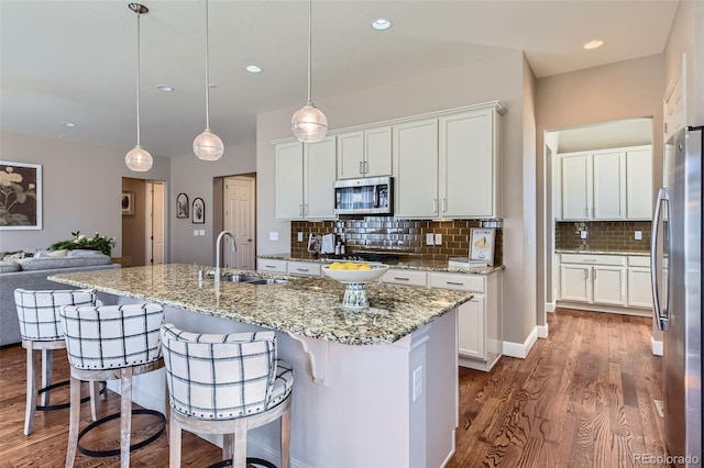 kitchen with a sink, dark wood-style floors, white cabinetry, appliances with stainless steel finishes, and a breakfast bar area